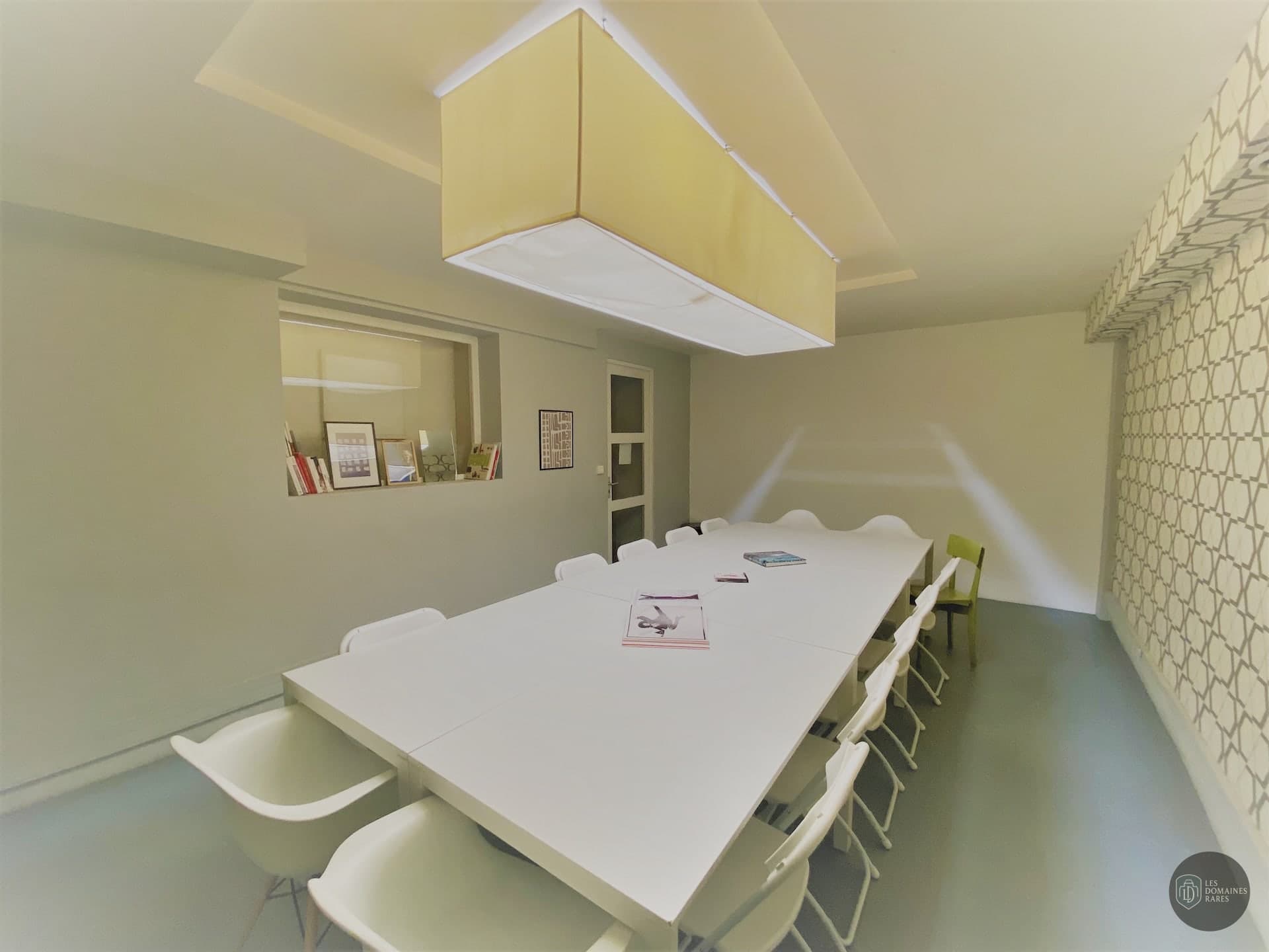 Salle de réunion avec longue table blanche