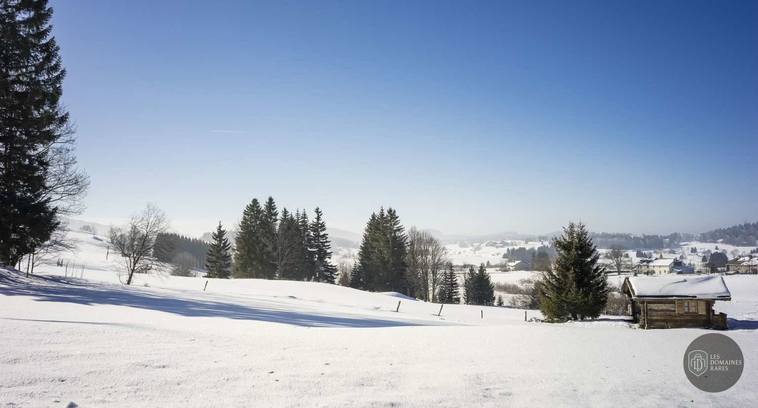 Paysage enneigé avec chalet au loin