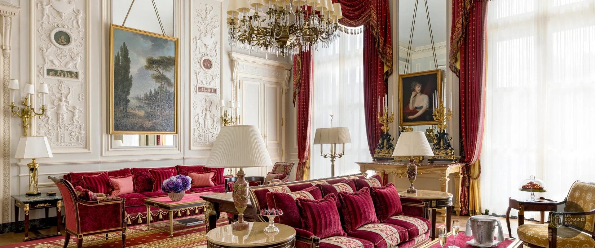 Salon luxueux avec canapés rouges et tableaux