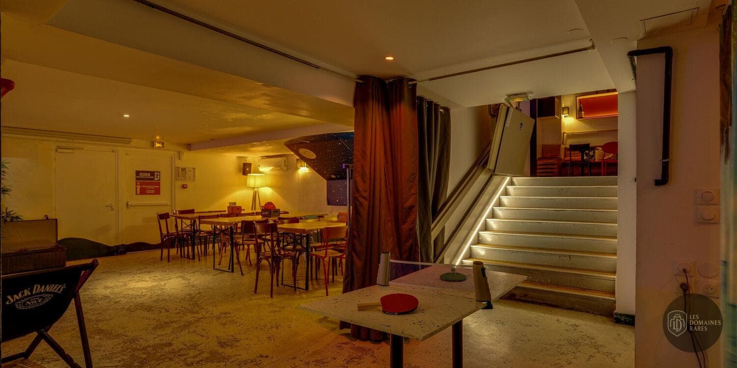Salle avec tables, ping-pong et escalier